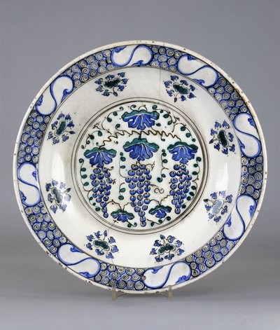 An Iznik pottery dish with a central roundel depicting three bunches of grapes and vine leaves, c.1570 by Turkish School