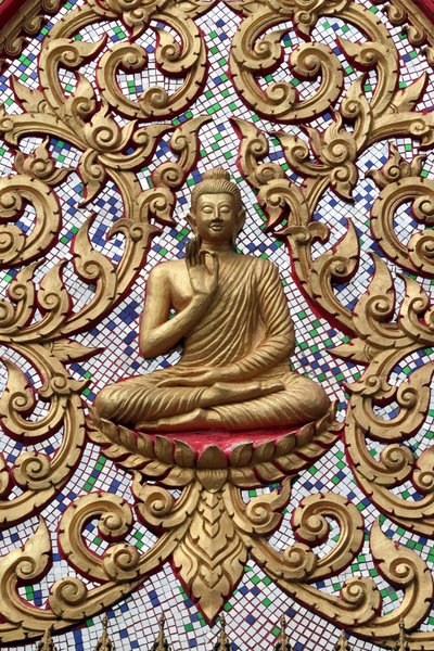 Entrance door ornamented with gold reliefs. The Teaching Buddha depicts a particular moment in the life of the Buddha, namely, the first sermon the Buddha gave after reaching Enlightenment, Vang Vieng, Laos by Unbekannt
