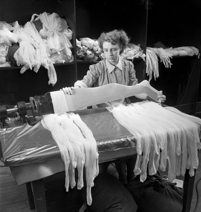 A female worker inspects woolen tights at the Aristoc mill by Unbekannt