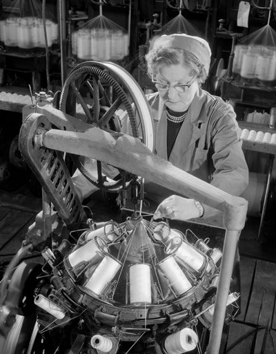 A middle aged female worker braiding reels of cables, Johnson and Phillips by Unbekannt