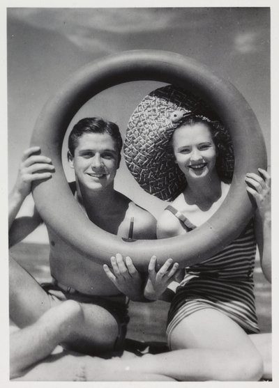 Man and woman looking through a rubber ring on beach, c 1935 by Unbekannt