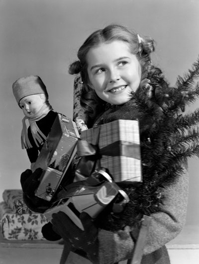 Young girl carrying an armful of Christmas presents, c 1950 by Unbekannt