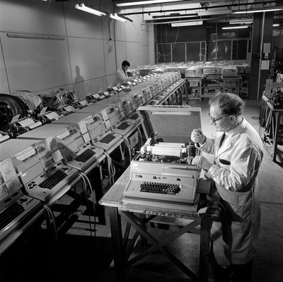 A line of completed Envoy telex machines are checked by Unbekannt