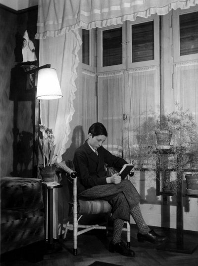 A teenager sitting in a bourgeois interior reads a book, 1915 by Unbekannter Künstler