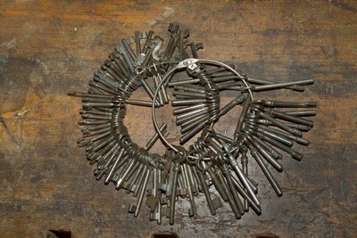 Large bunch of old keys on ring on wooden desk by Unbekannt