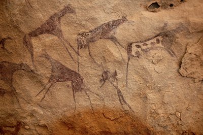 Rock art, Prehistory: Rock painting of a group of cattle and polychrome characters in an ornate shelter, in the Uweinat massif, Sudan (Period from 8000 to 3000 years BC). Photography by Unbekannt