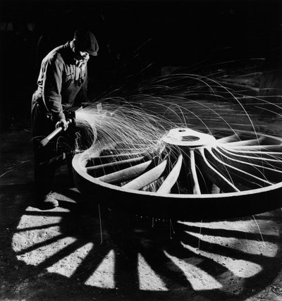 Sparks fly as man grinds locomotive wheel at Darlaston foundry by Unbekannt