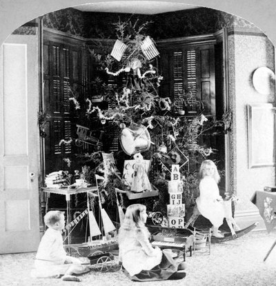 Children gathered at the foot of the tree surrounded by gifts on Christmas morning by Unknown photographer