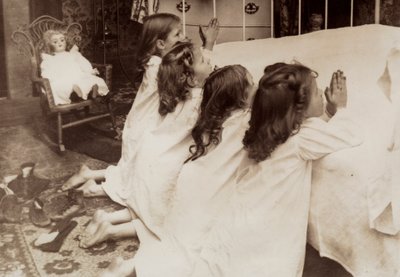 Four little girls kneeling at the side of a bed as they say their evening prayer by Unknown photographer