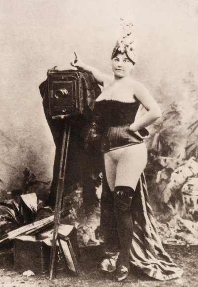 Portrait of a partially nude woman leaning on an antique camera by Unknown photographer