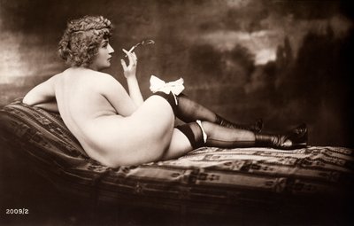 Portrait of a young woman posing naked, with her back turned, as she smokes a cigarette by Unknown photographer