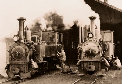 Two steam locomotives being maintained by two workers by Unknown photographer