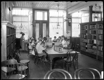 Children reading in the reading room of an unidentified branch of the Queens Borough Public Library, c.1910 by William Davis Hassler