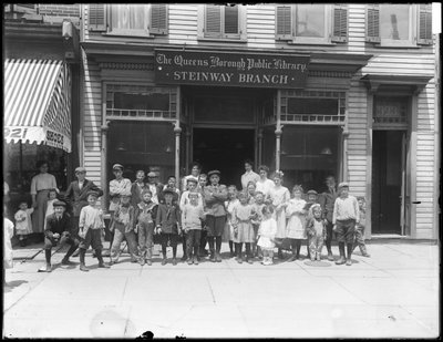 Group portrait of children in front of the Steinway branch of the Queens Borough Public Library by William Davis Hassler
