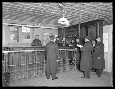 Interior of Unidentified Police Station, Showing Officers and Front Desk, c.1913-14 by William Davis Hassler