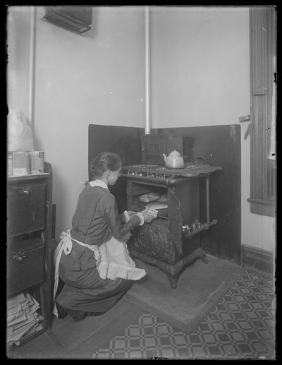 Miss Bates taking bread from the oven by William Davis Hassler