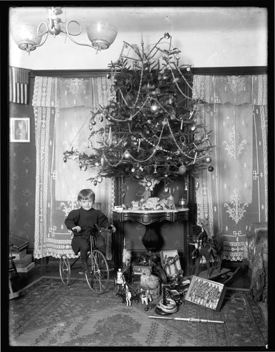 Seymour Boy Posed Seated on Tricycle Beside Christmas Tree in Parlor, Christmas 1912 by William Davis Hassler
