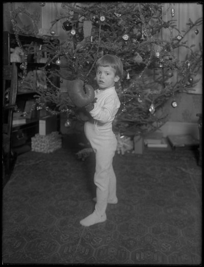 Unidentified Child Standing in Front of a Christmas Tree Wearing Boxing Gloves, 1915-16 by William Davis Hassler