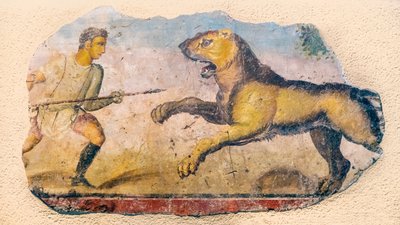 A Roman hunter confronting a charging lion. by . .