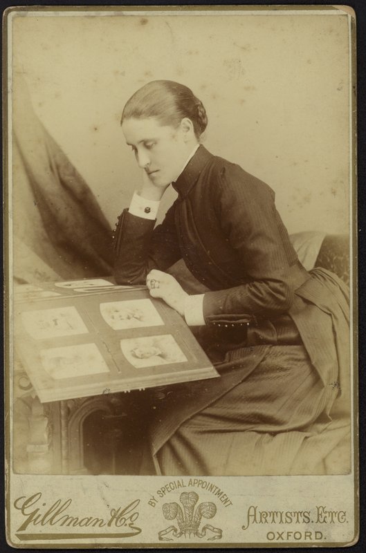 Figure of a woman sitting inspecting a photograph album by English Photographer