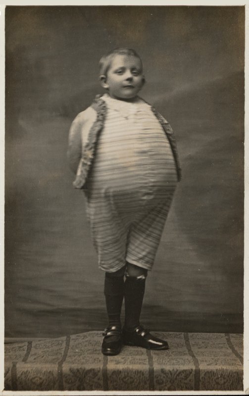 School Boy, Dressed Up to Have a Very Large Stomach by English Photographer
