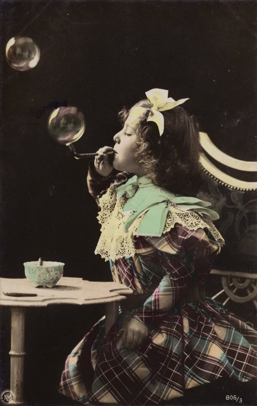 A little girl blowing bubbles from a pipe by French Photographer
