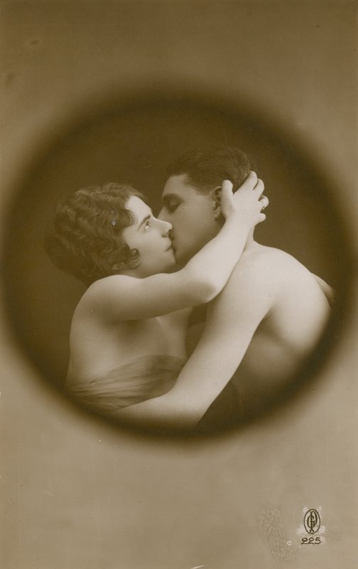 Young man and woman kissing as viewed through a peephole by French Photographer
