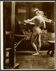 Female Nude Model Standing in Studio Holding a Sketchbook