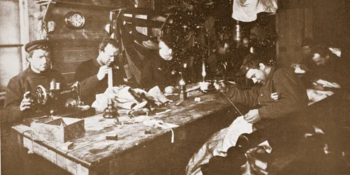 In the Hut during Mid-Winter, the Men Engaged in Sewing Furs for Clothing to be Used in Springtime Sledging, pub. London 1907