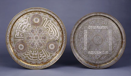 Two gold, copper and silver inlaid brass circular trays, decorated with arabesques and inscriptions, late 19th century
