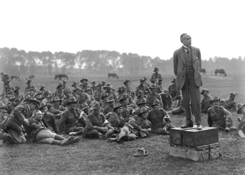 The Right Honourable William Morris (Billy) Hughes, standing on a platform composed of four ammunition boxes, addressing a gathering of the 5th Australian Field Ambulance, near La Motte
