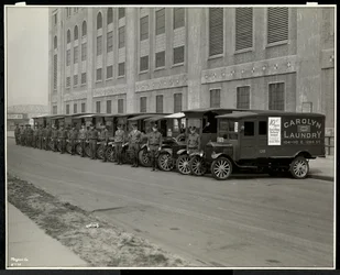 A line of delivery trucks parked outside the Carolyn Laundry at 111 East 128th Street, East Harlem, New York, 1929