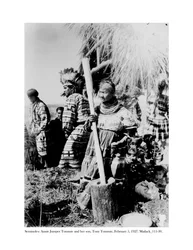 Annie Jumper Tommie Using a Mortar and Pestle to Make Cornmeal, and Her Son, Tony Tommie, Wearing an Eagle Feather Bonnet
