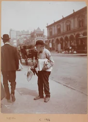 A man standing on the sidewalk of Broadway between 34th St. and 35th St. holding The Evening Telegram newspaper