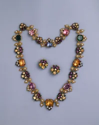 A fine Regency gold and jewelled necklace set with cushion-cut topaz, amethysts, pink tourmalines, emeralds, sapphires and peridots, with a pair of flowerhead earrings, c.1810