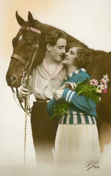 Couple about to kiss, standing by brown horse