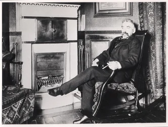 Stephane Mallarme (1842-98) seated by the fireplace at his home on Rue de Rome, Paris