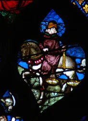 The west rose window depicting a scene from the Book of Revelation: A horseman, his horse not black as in the text, carrying the scales to measure the wheat and barley (6:5)