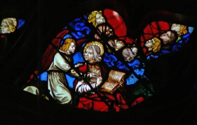 The west rose window depicting a scene from the Book of Revelation: Heads of the seven thunders in a blue cloud and St John being forbidden to write