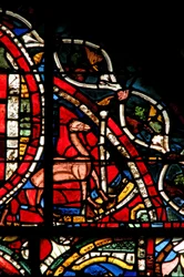 Window depicting a scene from the Prodigal Son story: a camel stands by to help him remove his inheritance