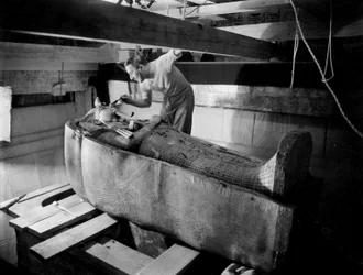 Discovery of the Tomb of Pharaoh Tutankhamun in the Valley of the Kings (Egypt): In Burial Chamber, Howard Carter Working on the Lid of the Second Coffin, October 1925, Photo by Harry Burton