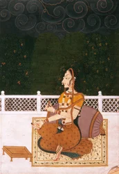 A beautiful woman seated against a bolster