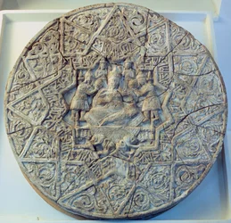 Sun disc depicting a king sitting cross-legged on a throne flanked by two angels in the centre, found at Ray, Iran