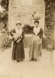 Two young women wearing traditional clothes and carrying terracotta jars near well, Marche, Italy, circa 1910