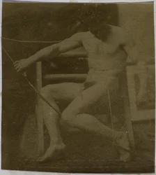 Study of a male nude model, sitting on a step, seen from the front with rope and bow on lap, in the studio of Jacques de Lalaing