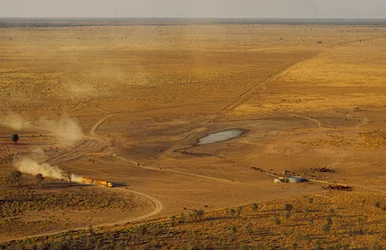 Road train carrying cattle crosses forbidding outback plateau, Western Australia