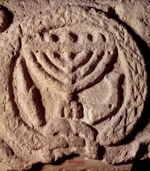 Judaism: architectural element in basalt of a synagogue decorated with a candlestick with seven branches (Menorah), palm and trumpet. From Transjordan. About 100 AD. Paris, Louvre Museum