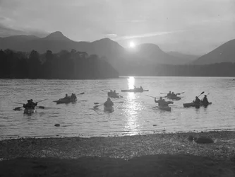 A view of people canoeing on Derwentwater at either sunrise or sunset