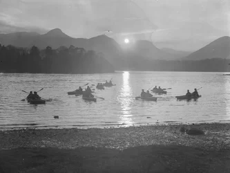 A view of people canoeing on Derwentwater at either sunrise or sunset