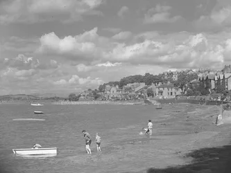 People playing in boats at high water in Arnside with Albion Hotel in background